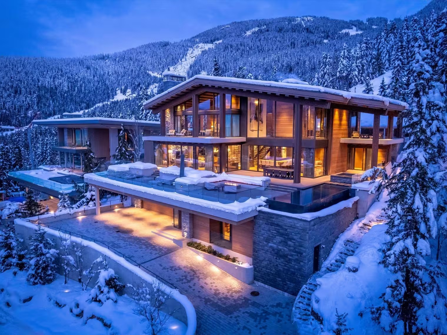 Ski-in, ski-out luxury chalet lit up at dusk on Whistler's mountain slopes