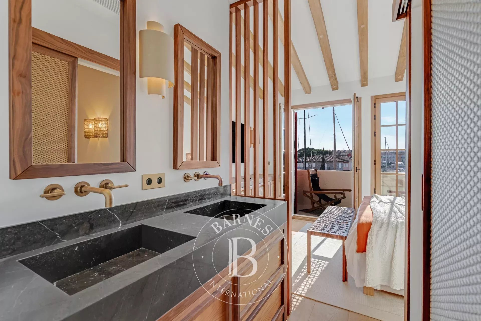 Primary suite with marble double vanity and private boat mooring visible through a slatted wood partition